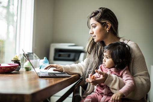 kobieta z dzieckiem używająca laptopa
